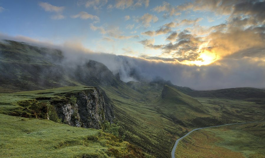 Green cliffs and mist over a mountain valley at sunset